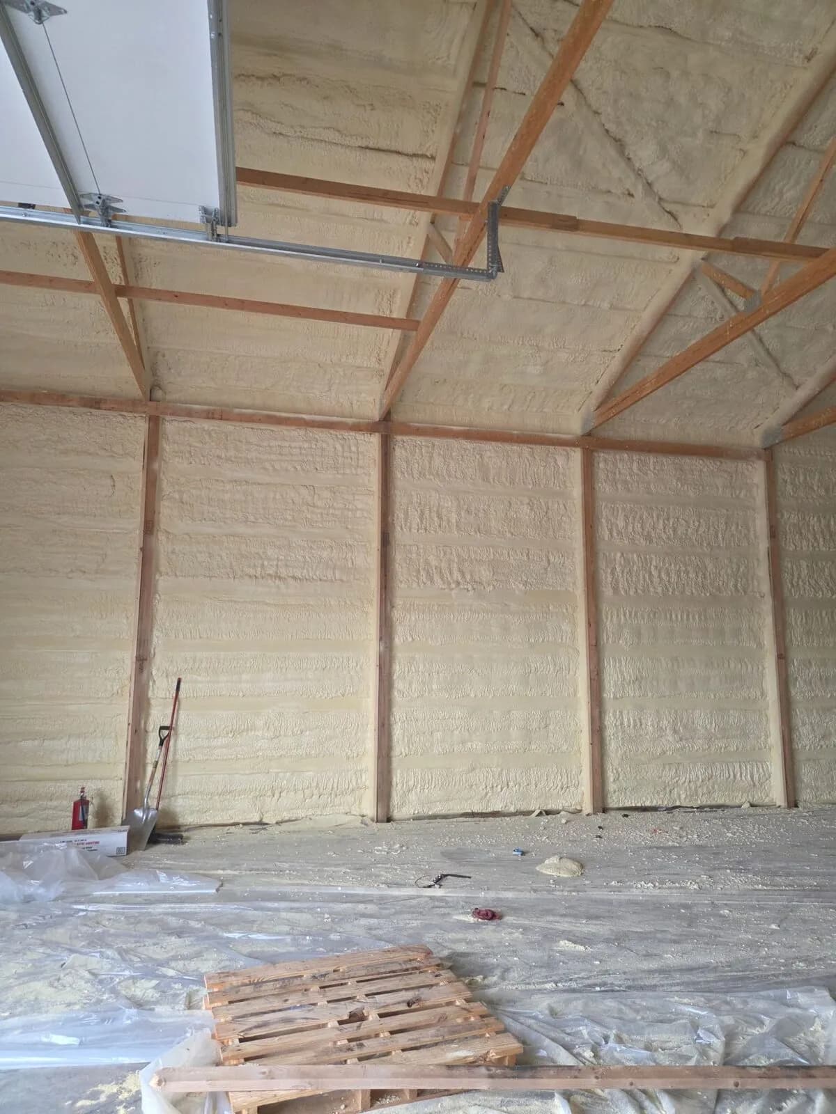 Spray foam insulation on garage walls and ceiling around the overhead door track